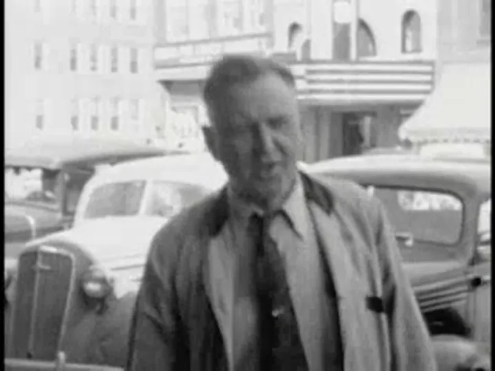Frame from a 1938 home movie at 320×240: a man in front of parked cars, enlarged with bicubic scaling